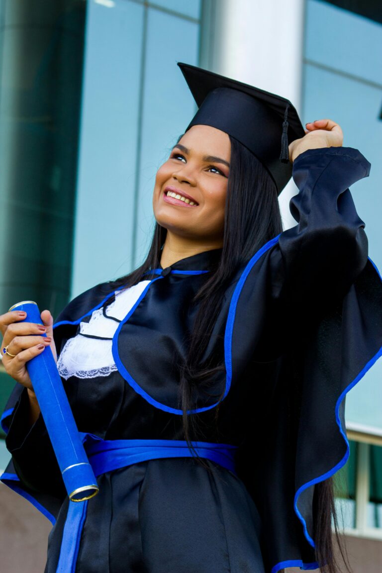 Young woman celebrating graduation with diploma in hand, wearing traditional cap and gown.